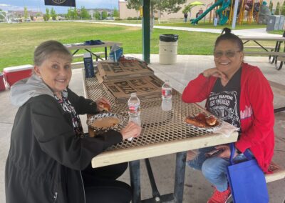 Two Union members sit at a picnic table eating pizza. They are looking at the camera and smiling.