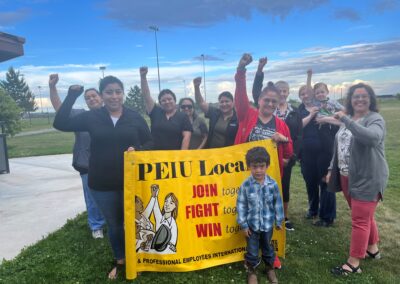 A group of Union members posts with an OPEIU Local 8 banner. The group is raising their fists in solidarity.